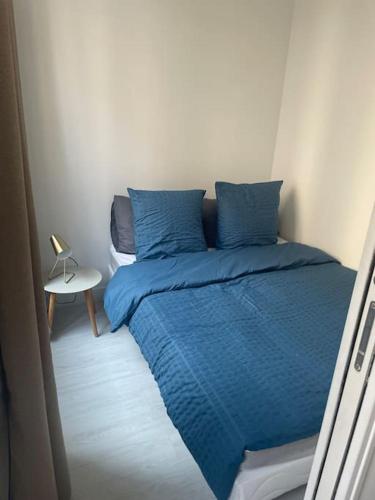 ein Bett mit blauen Kissen in einem kleinen Zimmer in der Unterkunft Paris Puteaux Centre - Jean Jaurés in Puteaux