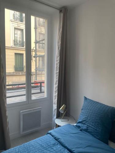 ein Schlafzimmer mit einem blauen Bett und einem Fenster in der Unterkunft Paris Puteaux Centre - Jean Jaurés in Puteaux