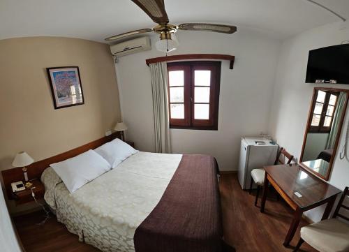 a bedroom with a bed and a desk and a window at Hotel Budapest in Piriápolis