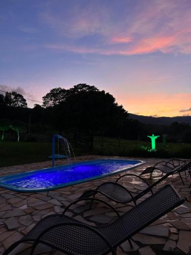 een zwembad met een fontein en stoelen bij zonsondergang bij Pousada Império de Minas in Capitólio