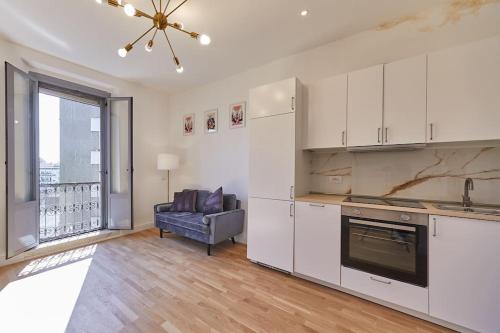 ミラノにあるLovely Apartmentの白いキャビネット付きのキッチン、ソファ付きのリビングルームが備わります。