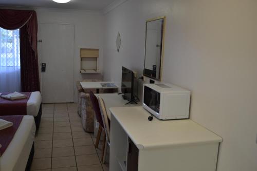 a room with a living room with a tv on a counter at Calico Court Motel in Tweed Heads