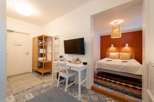 een slaapkamer met een bed en een bureau met een televisie bij Hotelli Kotola in Kotka