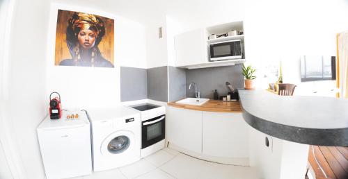una cucina bianca con lavatrice e asciugatrice di Élégant Studio proche de Paris et Disneyland a Villemomble