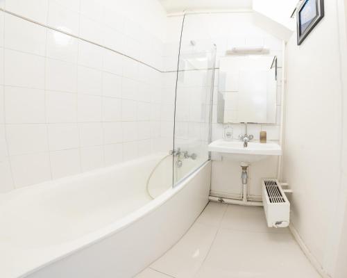Un baño blanco con bañera y lavabo. en Élégant Studio proche de Paris et Disneyland, en Villemomble