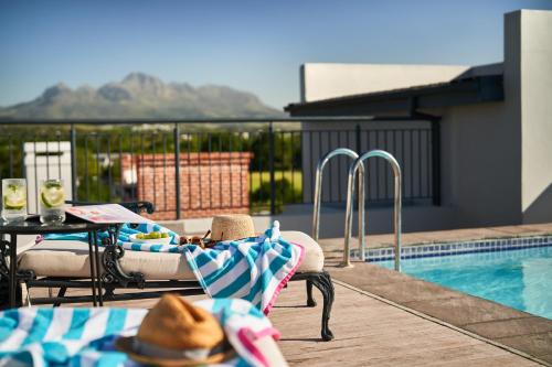 einen Pool mit einem Stuhl und einem Tisch mit einem Hut in der Unterkunft The Den Apartments by Raw Africa Collection in Stellenbosch