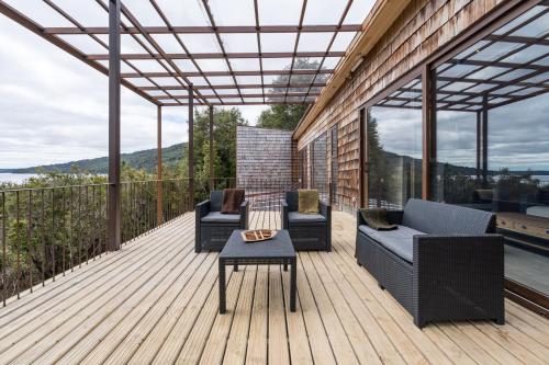 a deck with two couches and a table on it at Casas Martín Pescador, Lago Huillinco, Chiloe in Chonchi