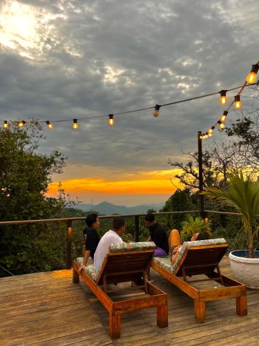a group of people sitting on a deck watching the sunset at La Veranda Hotel & Restaurant in Minca