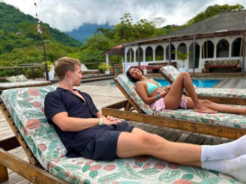 two people sitting on lounge chairs by a pool at La Veranda Hotel & Restaurant in Minca