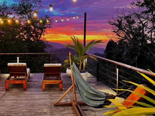 a hammock and chairs on a deck with a sunset at La Veranda Hotel & Restaurant in Minca