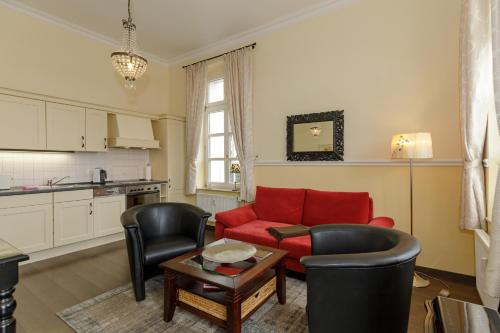 een woonkamer met een rode bank en stoelen bij Gutsschloss Rerik, "Belle Etage" in Rerik