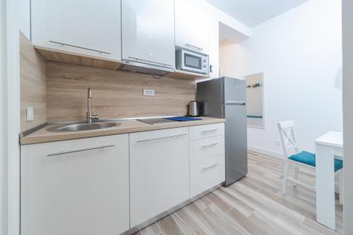 a kitchen with white cabinets and a stainless steel refrigerator at La barca apartments in Becici