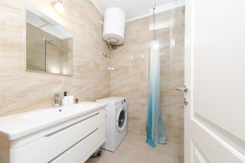 a bathroom with a washing machine and a sink at La barca apartments in Becici
