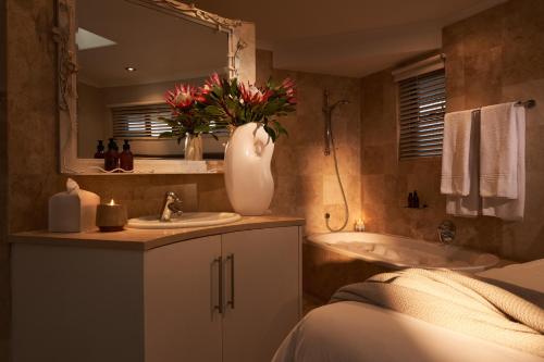 a bathroom with a sink and a tub and a vase with flowers at 22 Eikehoff Apartment in Stellenbosch