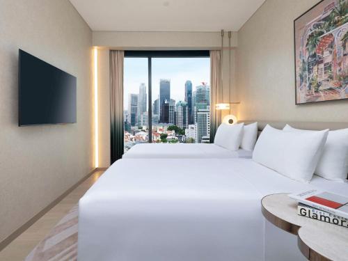 a hotel room with two beds and a large window at Mondrian Singapore Duxton in Singapore