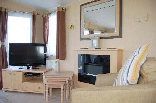 a living room with a flat screen tv and a couch at Caravan 251 Bryn Y Mor Beach Side Park in Tywyn