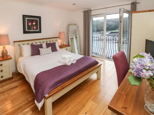 a bedroom with a bed and a balcony at Curlew in Milford Haven