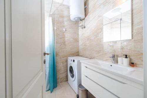 a bathroom with a washing machine and a sink at La barca apartments in Becici