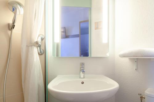 La salle de bains est pourvue d'un lavabo blanc et d'un miroir. dans l'établissement B&B HOTEL Maurepas, à Maurepas