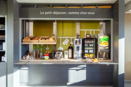 a kitchen with a counter with food and a refrigerator at B&B HOTEL Maurepas in Maurepas