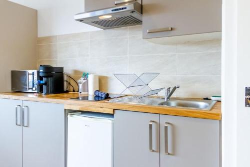 une cuisine avec des armoires blanches et un évier dans l'établissement ZenBNB / Azur / Proche Tram / Studio / Balcon Privé, à Annemasse