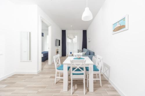 a white dining room with a white table and chairs at La barca apartments in Becici