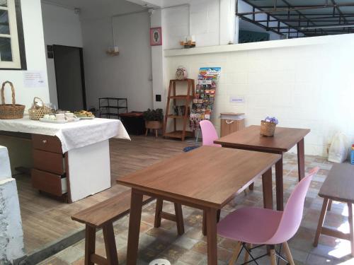 a room with two wooden tables and pink chairs at Wayside Guesthouse in Chiang Mai