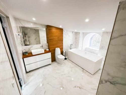 a bathroom with a tub and a toilet and a sink at Timber Hotel in Shchūchīnsk