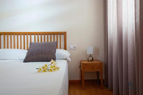 a bedroom with a bed with a pillow and flowers on it at Living4malaga Guevara Apartment in Málaga