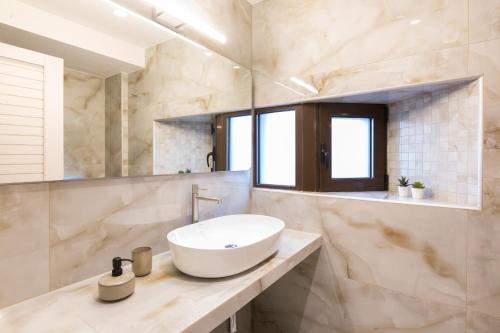 La salle de bains est pourvue d'un lavabo blanc et d'un miroir. dans l'établissement Antigoni's Seaside Lodge, a beach retreat!, à Réthymnon