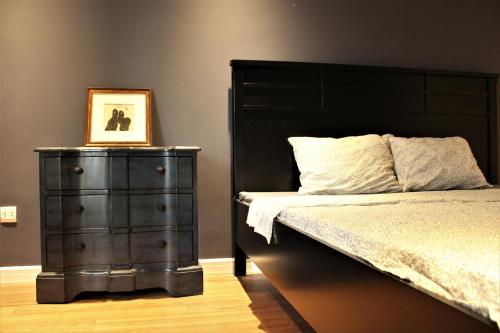 a bedroom with a bed and a picture on a dresser at D’Leroi Soleil - Westlake Suite & Apartment in Hanoi
