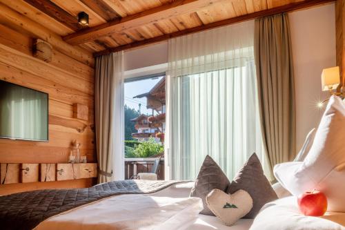 um quarto com uma cama e uma grande janela em Chalet Elisabeth dolomites alpin & charme em Selva di Val Gardena