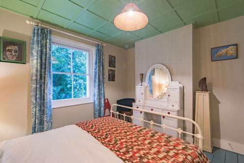 a bedroom with a bed with a mirror and a window at Folkestone Terrace - quirky vibe holiday home in Kent