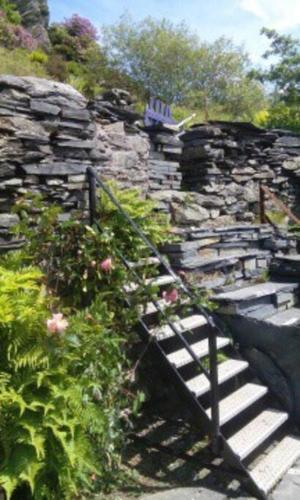 a stone wall and stairs in a garden at Cosy terrace cottage built into the mountain side. in Blaenau-Ffestiniog