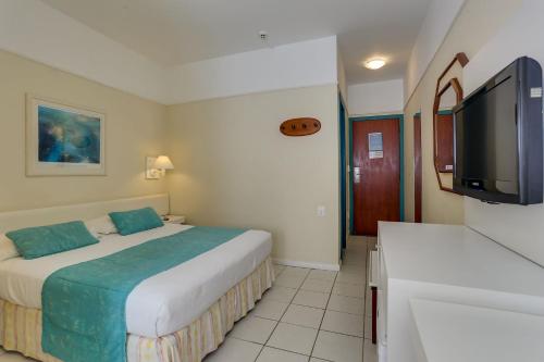 a hotel room with two beds and a flat screen tv at Costa Norte Ponta das Canas Hotel in Florianópolis