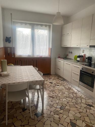 eine Küche mit einem Tisch und eine Küche mit weißen Schränken in der Unterkunft Appartamento " Le Farfalle " in Santorso
