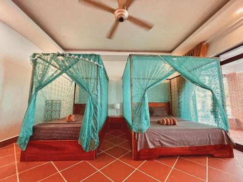 two beds in a room with a ceiling fan at Paradise Villas Koh Rong Sanloem in Koh Rong Sanloem