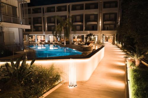 a large building with a swimming pool at night at Flisvos Royal Hotel & Suites in Tolo