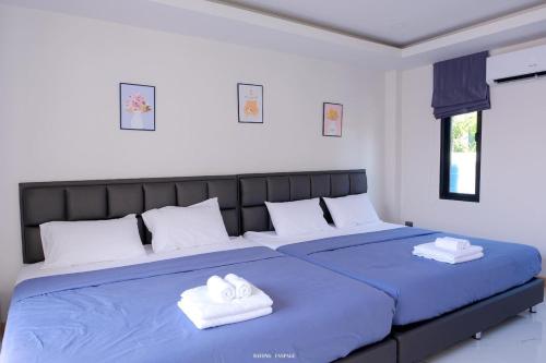 a bedroom with a blue bed with two towels on it at F&F pool villa Rayong in Rayong