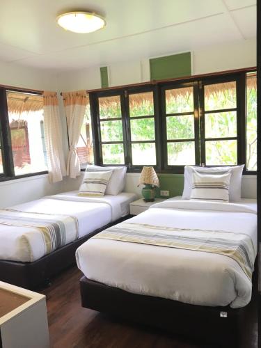 two beds sitting in a room with windows at Suan Bankrut Beach Resort in Ban Krut