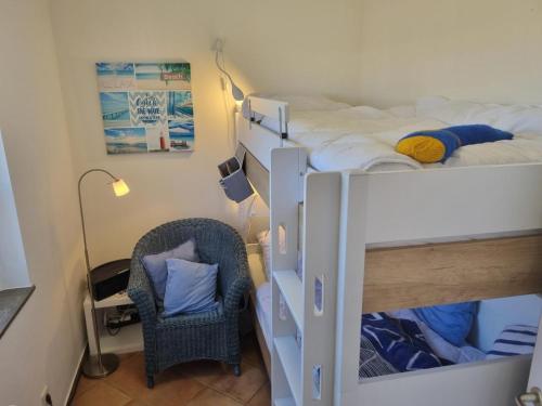 - une chambre avec 2 lits superposés et une chaise dans l'établissement Ferienhaus-Schirmqualle, à Dornumersiel
