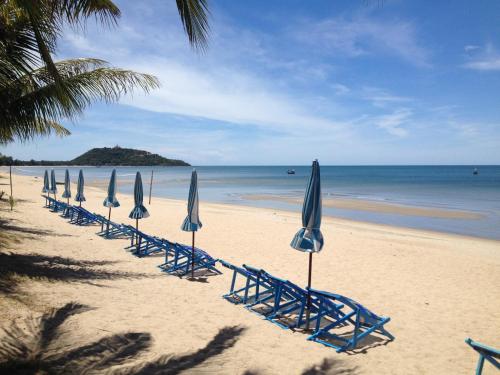 a row of beach chairs with umbrellas on a beach at Suan Bankrut Beach Resort in Ban Krut