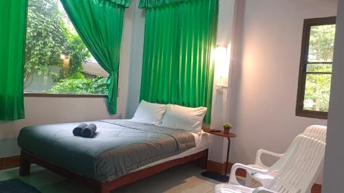 1 dormitorio con 1 cama con cortinas verdes y ventana en Mountain View Hostel - Krabi, en Krabi