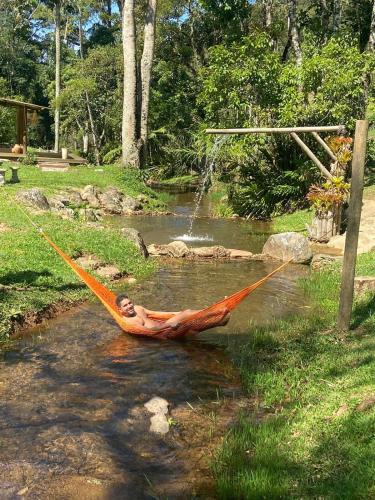 a man laying in a hammock in a river at Matha Pousada e Bistrô in Lumiar