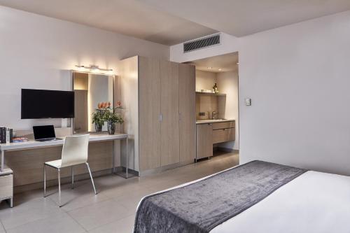 a bedroom with a bed and a desk with a computer at Atlantica Mikri Poli Crete in Makry Gialos