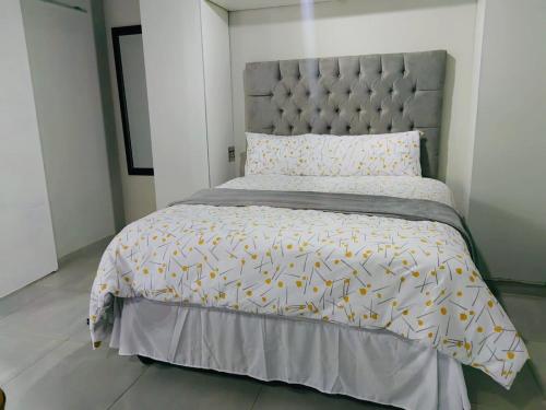 a bedroom with a large bed with a gray headboard at Tranquil Escapes Bramley in Johannesburg
