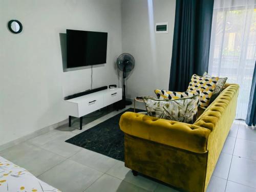 a living room with a yellow couch and a flat screen tv at Tranquil Escapes Bramley in Johannesburg