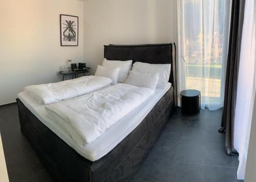 een groot bed met witte lakens en kussens in een slaapkamer bij Motel by Maier Feldkirch - kontaktloser Check-in in Feldkirch