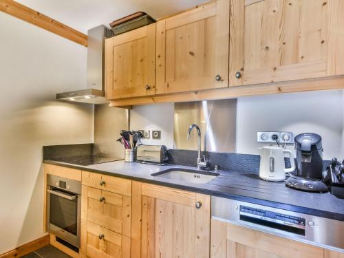 une cuisine avec des armoires en bois et un évier dans l'établissement Splendide T4 centre station, proche pistes, restaurants - 7 pers - FR-1-685-17, aux Gets