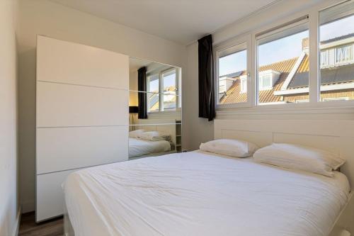 a bedroom with a white bed and two windows at Nice apartment in the city center Kerkakker 1 in Eindhoven